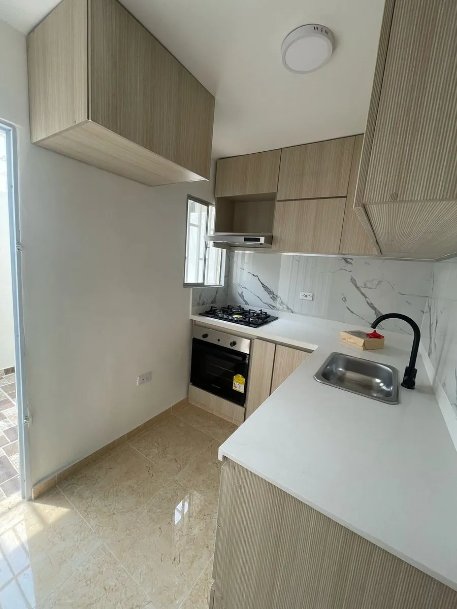Cocina integral con gabinetes en madera, mesón blanco y horno empotrado