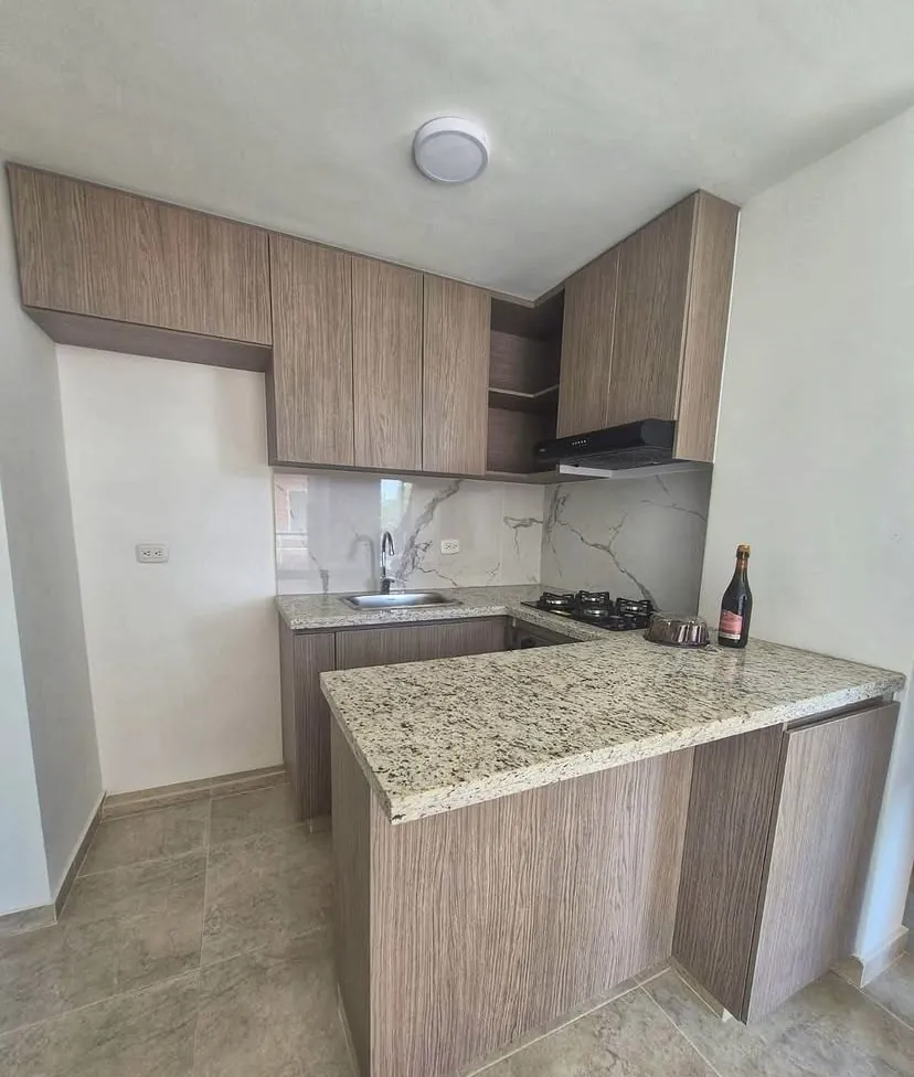 Cocina en L con barra de granito claro y gabinetes en madera