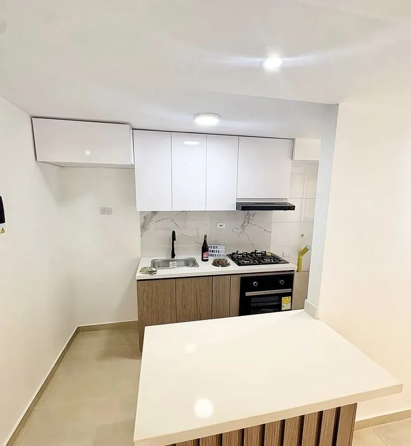 Cocina blanca con isla de mesón claro y frente en listones de madera