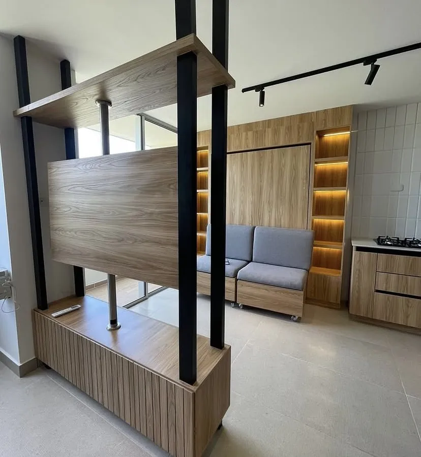Sala del apartamento modelo Río Living: mueble divisor giratorio para el televisor y repisas con luz cálida